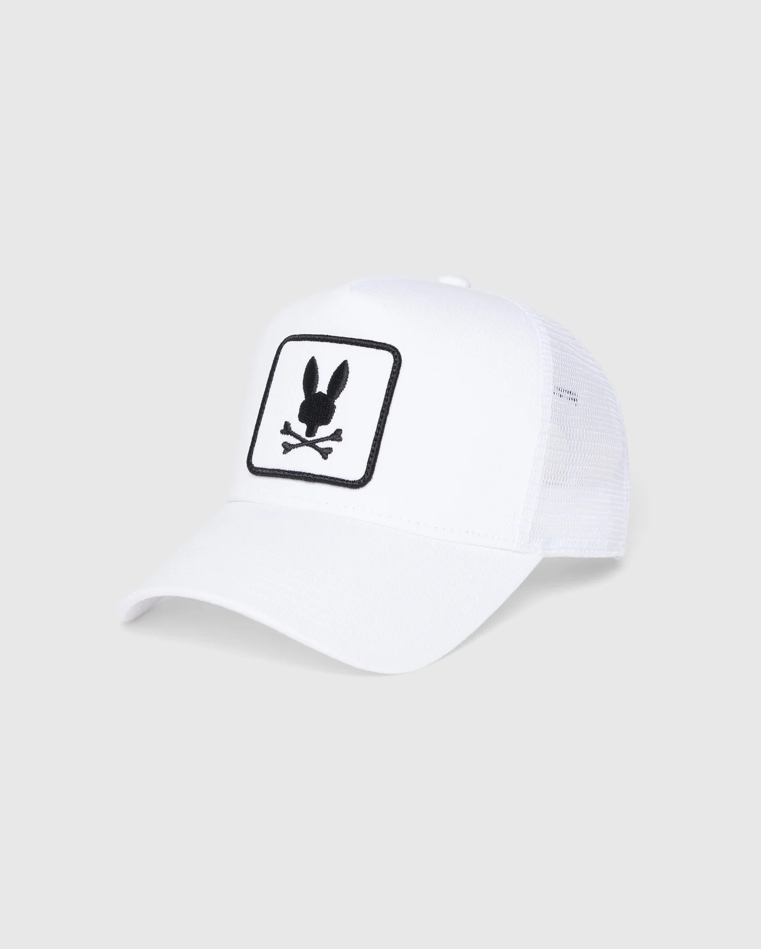 The KIDS BUNNY PATCH TRUCKER CAP - B0A965C200 by Psycho Bunny is a white mesh baseball hat displaying the brand's official logo. The patch features a playful bunny head above crossed bones silhouette, adding an edgy twist to its classic design.