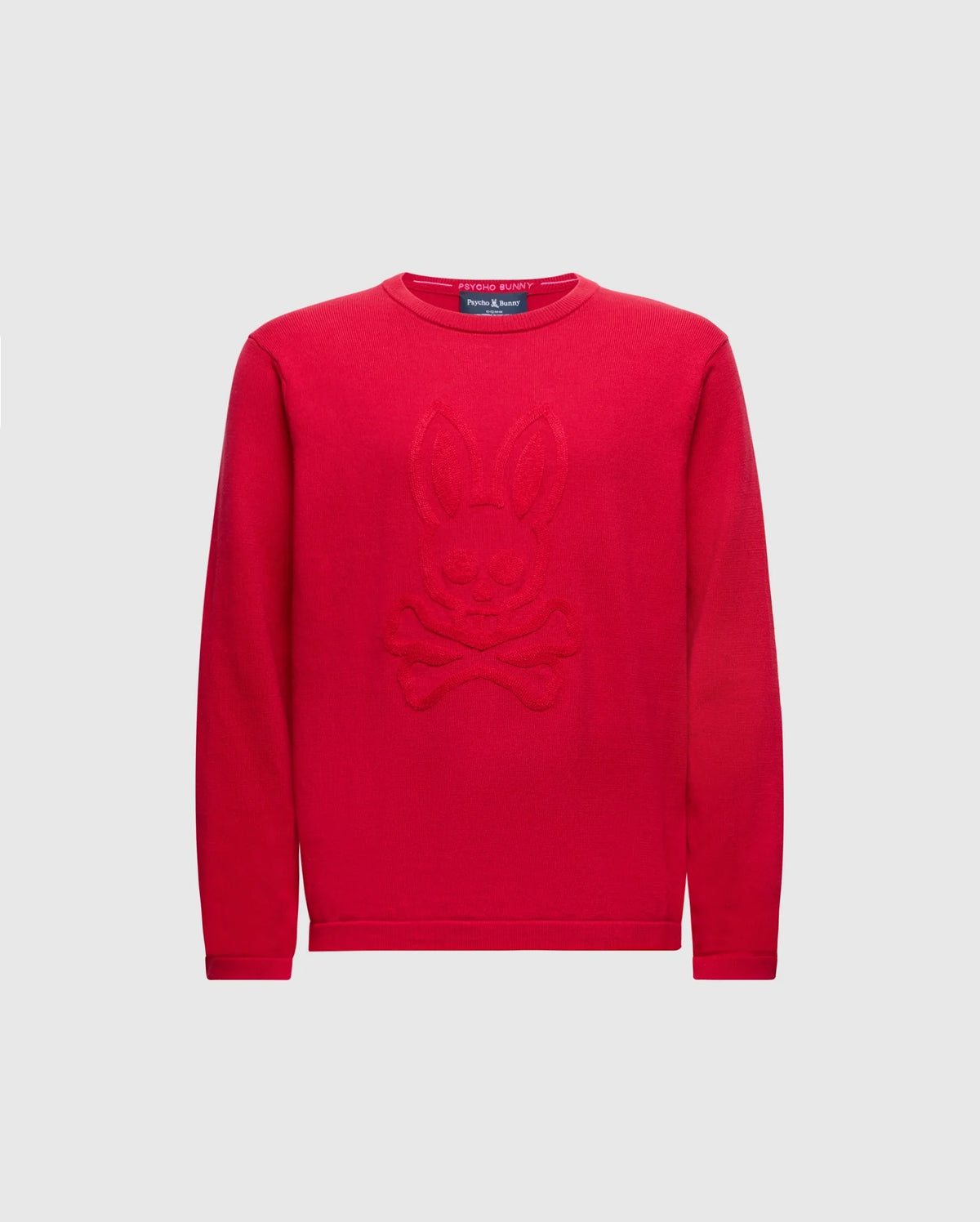 The KIDS COORY CHAINSTITCH COTTON SWEATER by Psycho Bunny features a vibrant design with a cartoon bunny and crossbones on fine cotton. It has long sleeves, a round neckline, and is set on a plain white background.