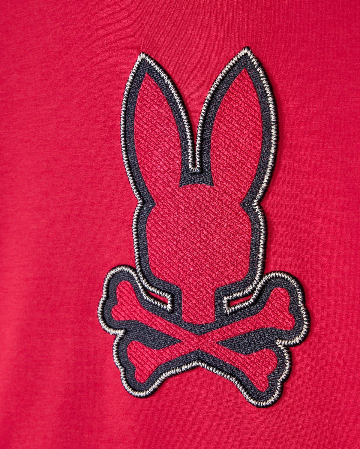 The Psycho Bunny KIDS WALTER LIGHTWEIGHT HOODIE - B0H476D200 is a red hoodie adorned with an embroidered patch showcasing a minimalist rabbit head above crossed bones, offering a modern twist on the traditional pirate skull and crossbones symbol. Made from Micro French terry fabric, it ensures ultimate comfort.