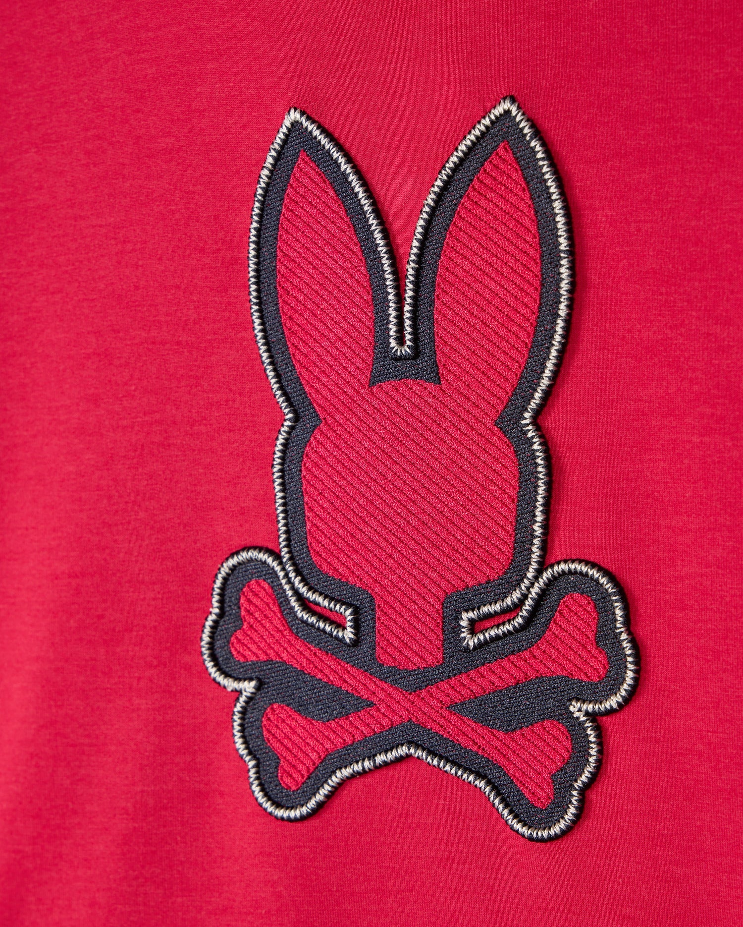 The Psycho Bunny KIDS WALTER LIGHTWEIGHT HOODIE - B0H476D200 is a red hoodie adorned with an embroidered patch showcasing a minimalist rabbit head above crossed bones, offering a modern twist on the traditional pirate skull and crossbones symbol. Made from Micro French terry fabric, it ensures ultimate comfort.