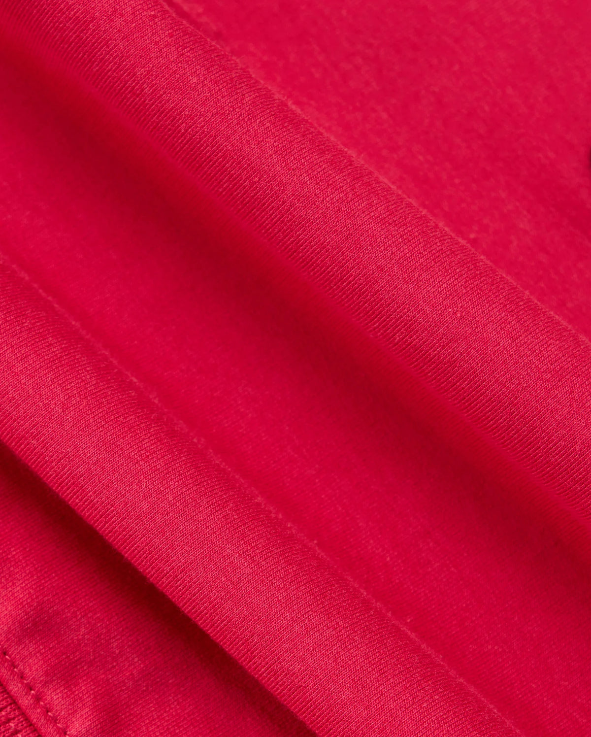 Close-up image of a vibrant red fabric with visible stitching, reminiscent of the stylish KIDS WALTER LIGHTWEIGHT HOODIE - B0H476D200 by Psycho Bunny. The texture appears smooth and tightly woven, similar to Micro French terry, while the lighting highlights the fabric's sheen.