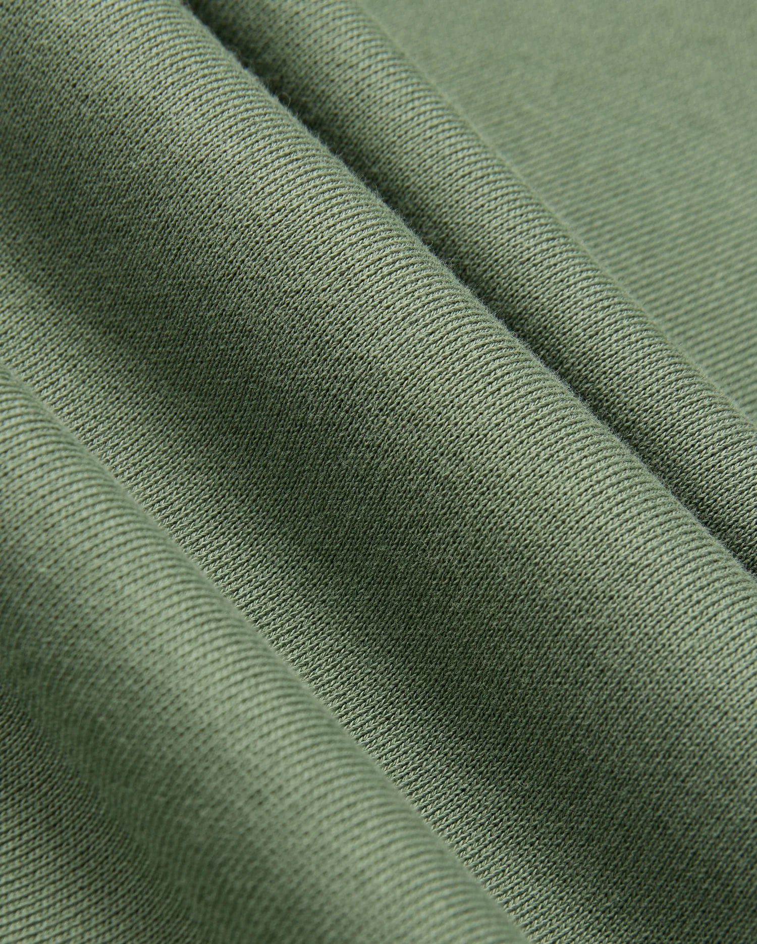 A close-up of olive green fabric with a ribbed texture, reminiscent of the KIDS PACIFIC CHENILLE HOODIE by Psycho Bunny. The fabric falls into soft folds, accentuating its smooth and slightly shiny surface similar to the chenille embroidery on this Psycho Bunny piece.