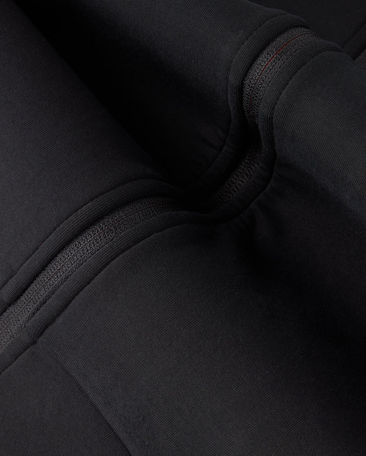 Close-up view of black fabric with detailed stitching and folds on the high-quality cotton-blend KIDS TRAVIS TRACK JACKET - B0J142D200 by Psycho Bunny. The texture and seams of the fabric are clearly visible.
