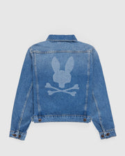 A light blue KIDS PATHE DENIM JACKET - B0J741X1CO from Psycho Bunny is shown from the back, featuring a unique design. The design, in a lighter denim wash, depicts a bunny head above two crossed bones, resembling a playful twist on the classic skull and crossbones symbol. The jacket is made from upcycled cotton for an eco-friendly touch.