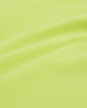 A close-up of the KIDS CLASSIC POLO - B0K001CRPC by Psycho Bunny shows a textured, lime green fabric with a subtle wave pattern, resembling classic piqué designs. Crafted from a breathable, slightly elastic mesh material like soft Pima cotton.