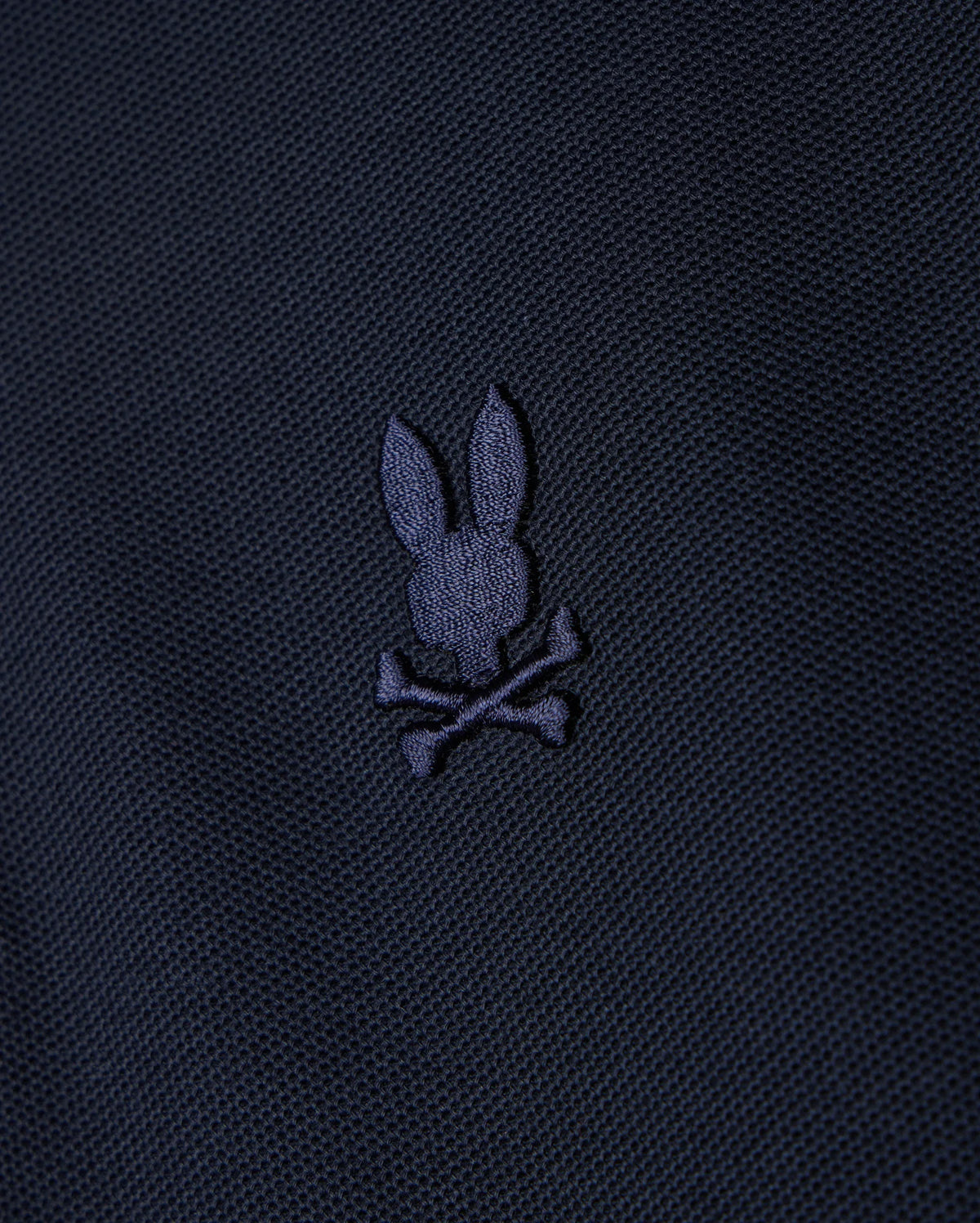 A KIDS CLASSIC PIQUE POLO SHIRT - B0K021AR00 by Psycho Bunny, featuring a dark fabric design with an embroidered chest Bunny logo depicting a bunny head and crossbones in a slightly lighter shade.