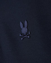 A KIDS CLASSIC PIQUE POLO SHIRT - B0K021AR00 by Psycho Bunny, featuring a dark fabric design with an embroidered chest Bunny logo depicting a bunny head and crossbones in a slightly lighter shade.