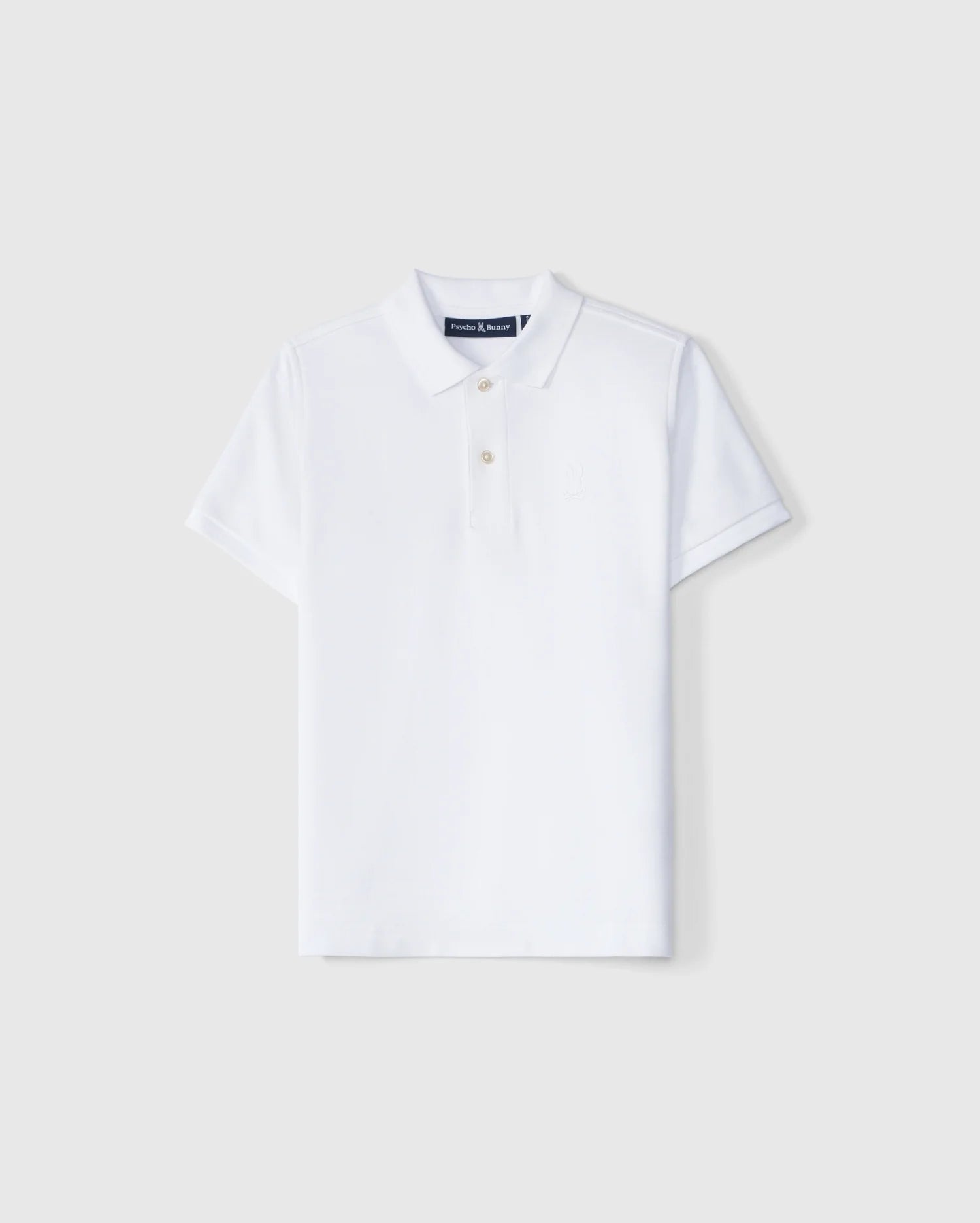A Psycho Bunny Kids Classic Pique Polo Shirt (B0K021AR00) features a plain white design on a light gray background, crafted from luxurious Pima cotton. It has short sleeves, a classic collar, three white buttons, and an embroidered Bunny logo.