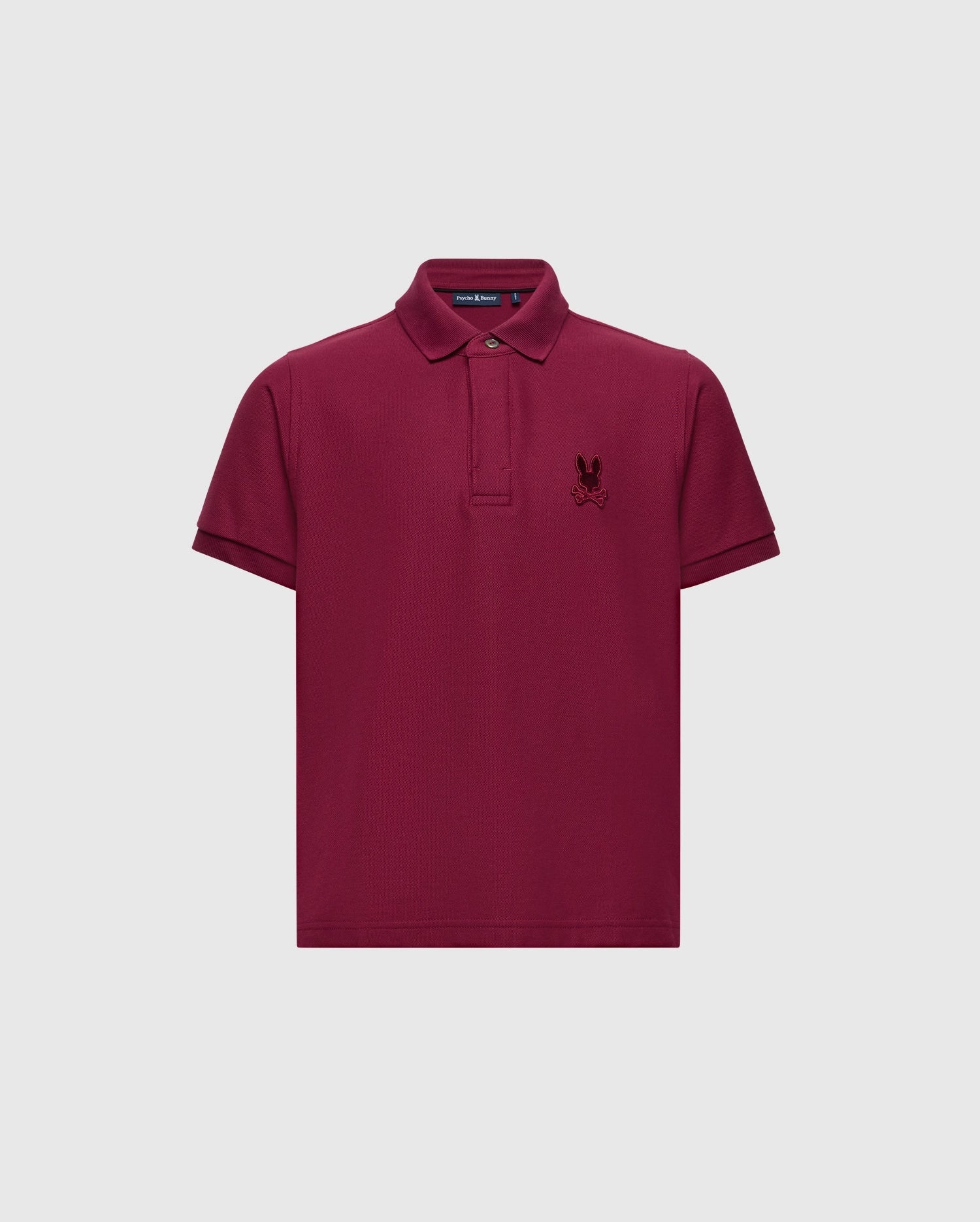 Introducing the KIDS BRANDSON PIQUE POLO - B0K108E200 by Psycho Bunny, a stylish maroon polo shirt for children. Crafted from soft Pima cotton, it showcases a small embroidered emblem on the left chest, complemented by a classic collar and button placket against a plain white backdrop.