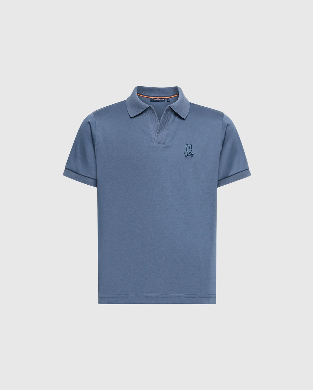 The KIDS BROADWAY PIMA INTERLOCK JOHNNY COLLAR POLO by Psycho Bunny features a blue short-sleeved design made from luxurious mercerized Pima cotton, a stylish Johnny collar, and a subtle embroidered logo on the left chest against a plain light grey background.