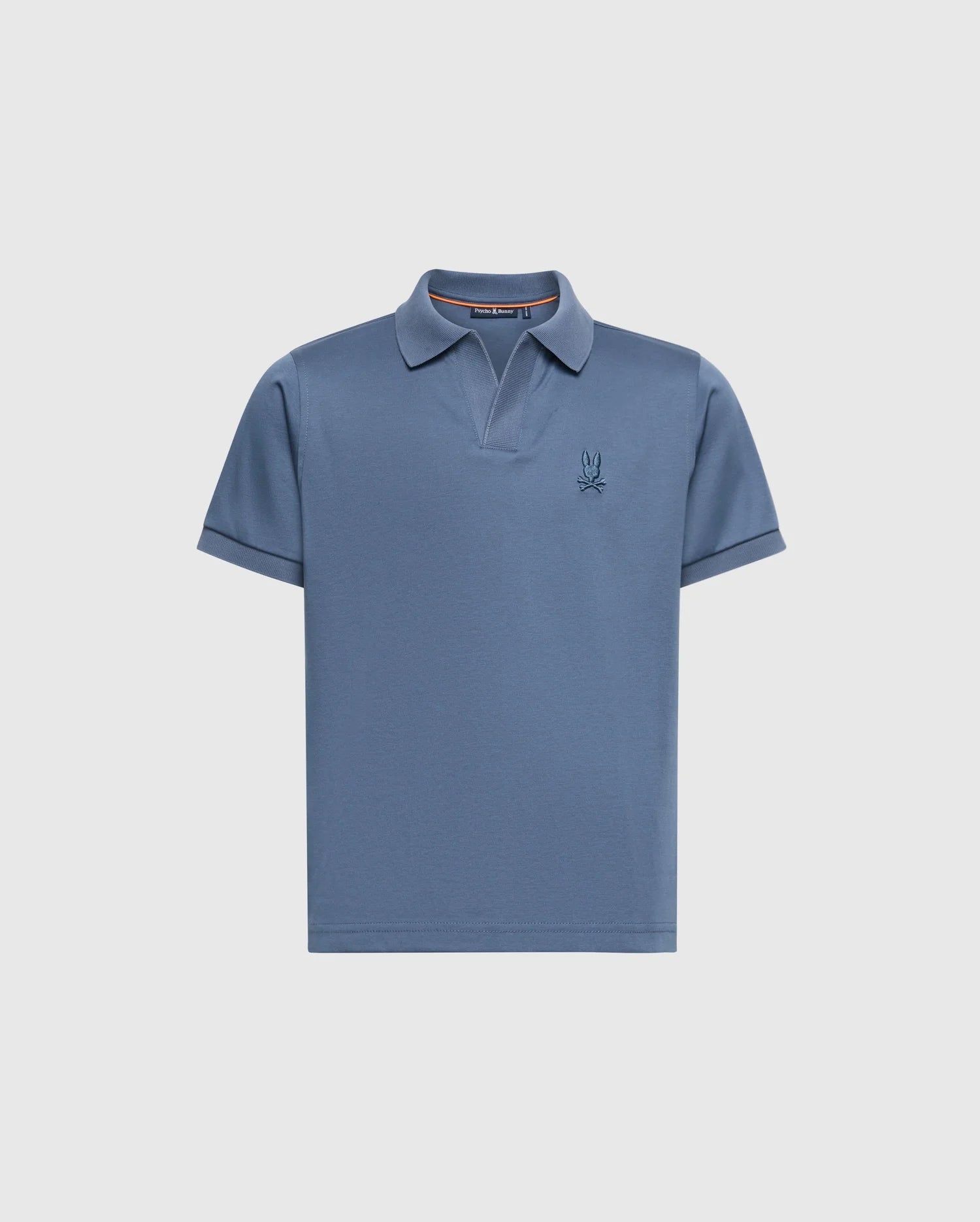 The KIDS BROADWAY PIMA INTERLOCK JOHNNY COLLAR POLO by Psycho Bunny features a blue short-sleeved design made from luxurious mercerized Pima cotton, a stylish Johnny collar, and a subtle embroidered logo on the left chest against a plain light grey background.
