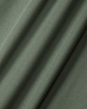 Close-up of green fabric with a mesh-like pattern, featuring diagonal folds and a textured surface that evokes the fine weave of the diamond piqué-patterned cuffs on the KIDS MALTON PIQUE POLO SHIRT by Psycho Bunny.