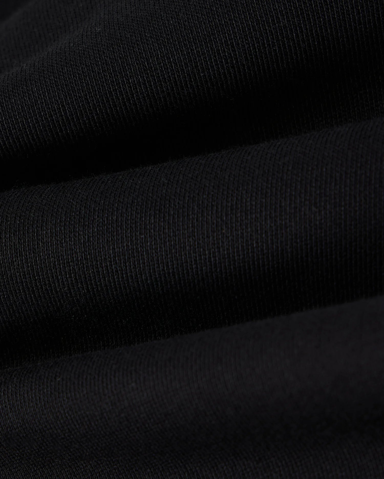Close-up view of the black cotton fleece fabric with visible ribbing and slight texture, creating a series of gentle horizontal waves, perfect for the Psycho Bunny KIDS LENOX REGULAR FIT SWEATPANT.