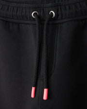 Close-up of the KIDS TRAVIS TRACK PANT - B0P143D200 by Psycho Bunny, showcasing black jogger pants with a drawstring featuring pink plastic aglets and metal eyelets, complemented by a side pocket. The elastic and comfortable material makes it ideal for kids' track pants.
