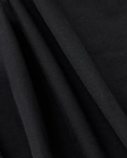 Close-up of draped black fabric with smooth texture and soft folds. The fabric is captured in a way that highlights its rich, deep color and fine, subtle weave, reminiscent of the elegance of the Psycho Bunny Kids Madison Commuter Pant - B0P395Z1WB—an appearance both sophisticated and timeless.