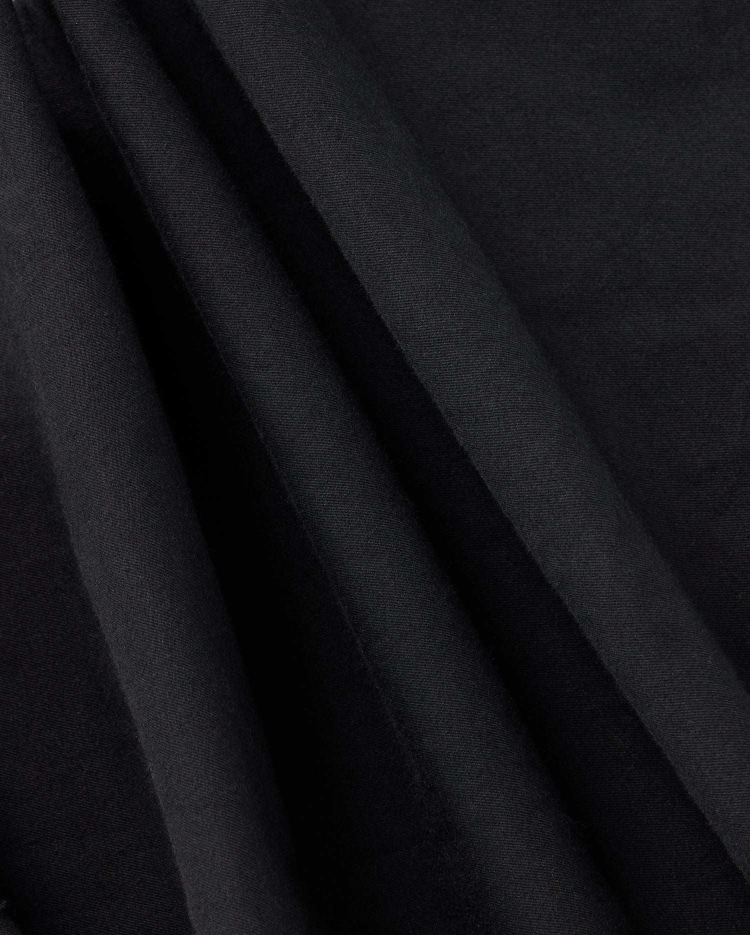 Close-up of draped black fabric with smooth texture and soft folds. The fabric is captured in a way that highlights its rich, deep color and fine, subtle weave, reminiscent of the elegance of the Psycho Bunny Kids Madison Commuter Pant - B0P395Z1WB—an appearance both sophisticated and timeless.