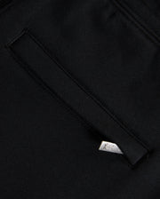 A close-up of black Psycho Bunny KIDS MONROE TWILL PATCH FLEECE SWEATPANTS showcases a welt pocket with a white tag featuring the logo. The slightly textured fabric and clean stitching evoke premium craftsmanship.