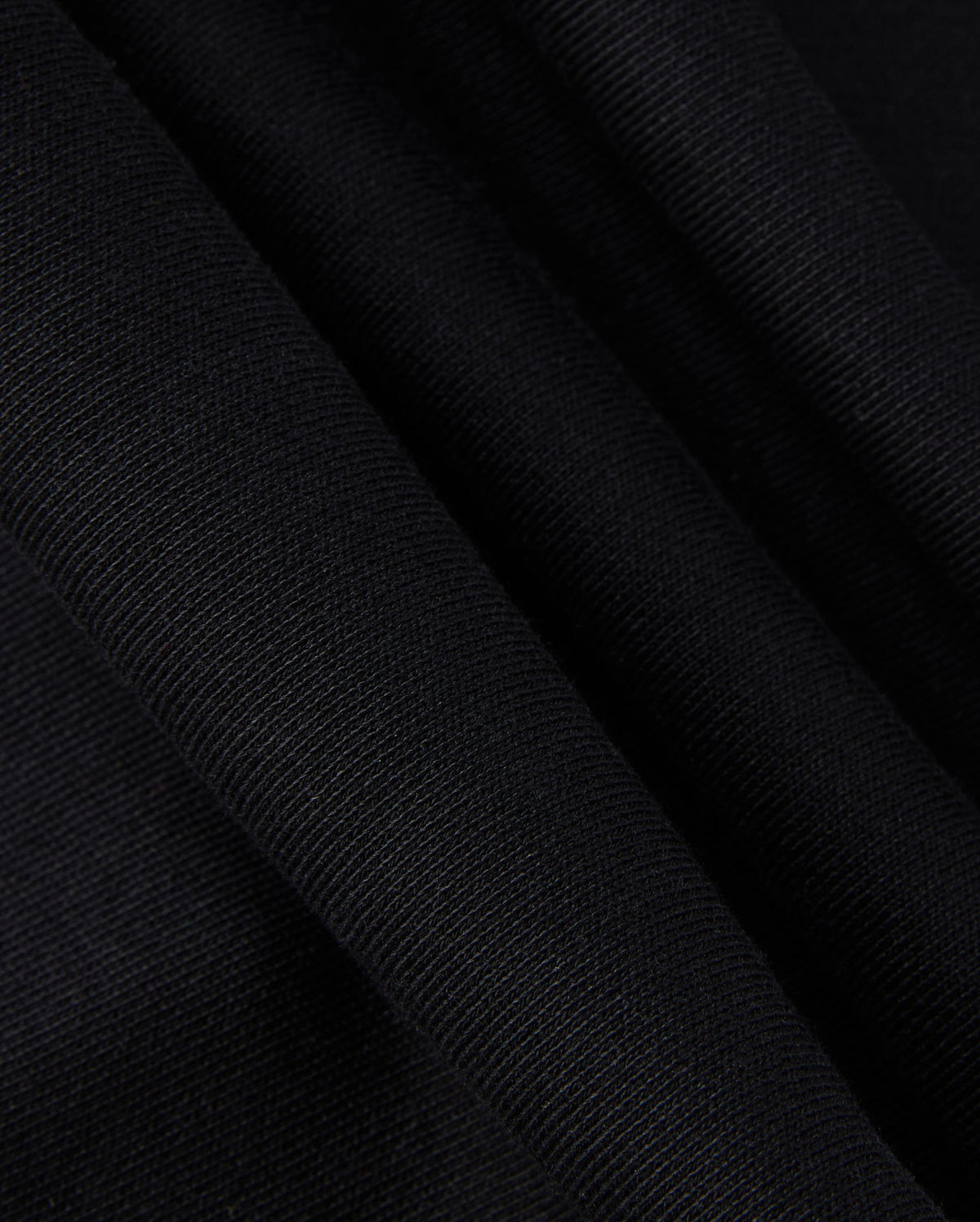A close-up of the KIDS MONROE TWILL PATCH FLEECE SWEATPANT by Psycho Bunny showcases the black textured fabric with folds, highlighting its weave and subtle sheen akin to luxury finishes.