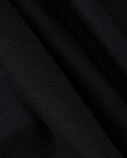 A close-up of the KIDS MONROE TWILL PATCH FLEECE SWEATPANT by Psycho Bunny showcases the black textured fabric with folds, highlighting its weave and subtle sheen akin to luxury finishes.