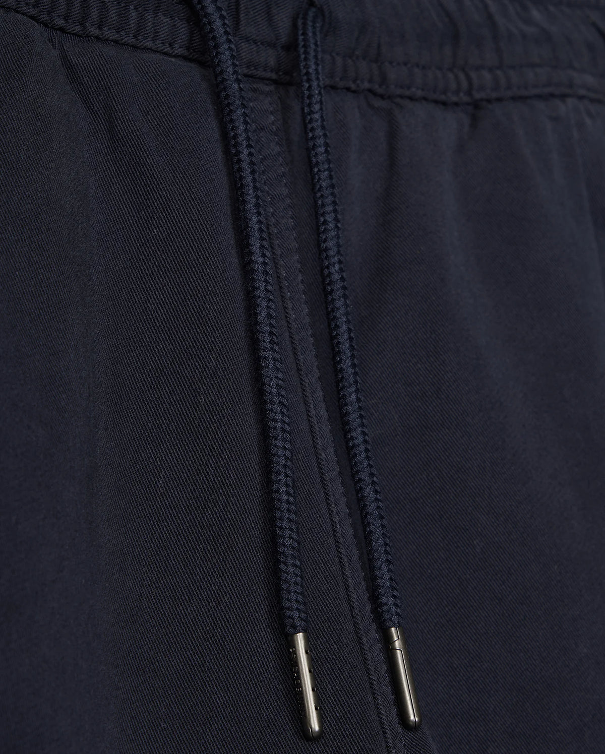 Close-up of a black fabric drawstring with metal aglets on Psycho Bunny's KIDS WILLIS STRETCH TENCEL SHORT - B0R239Y1WB clothing, focusing on the texture and details of the material and drawstring.