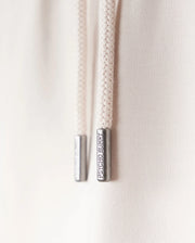Close-up of two cream-colored drawstring cords with metal tips engraved with "LIMITED EDITION." The cords, part of a Psycho Bunny KIDS LIVINGSTON TERRY SWEATSHORT - B0R408B200, hang against a soft, light background.