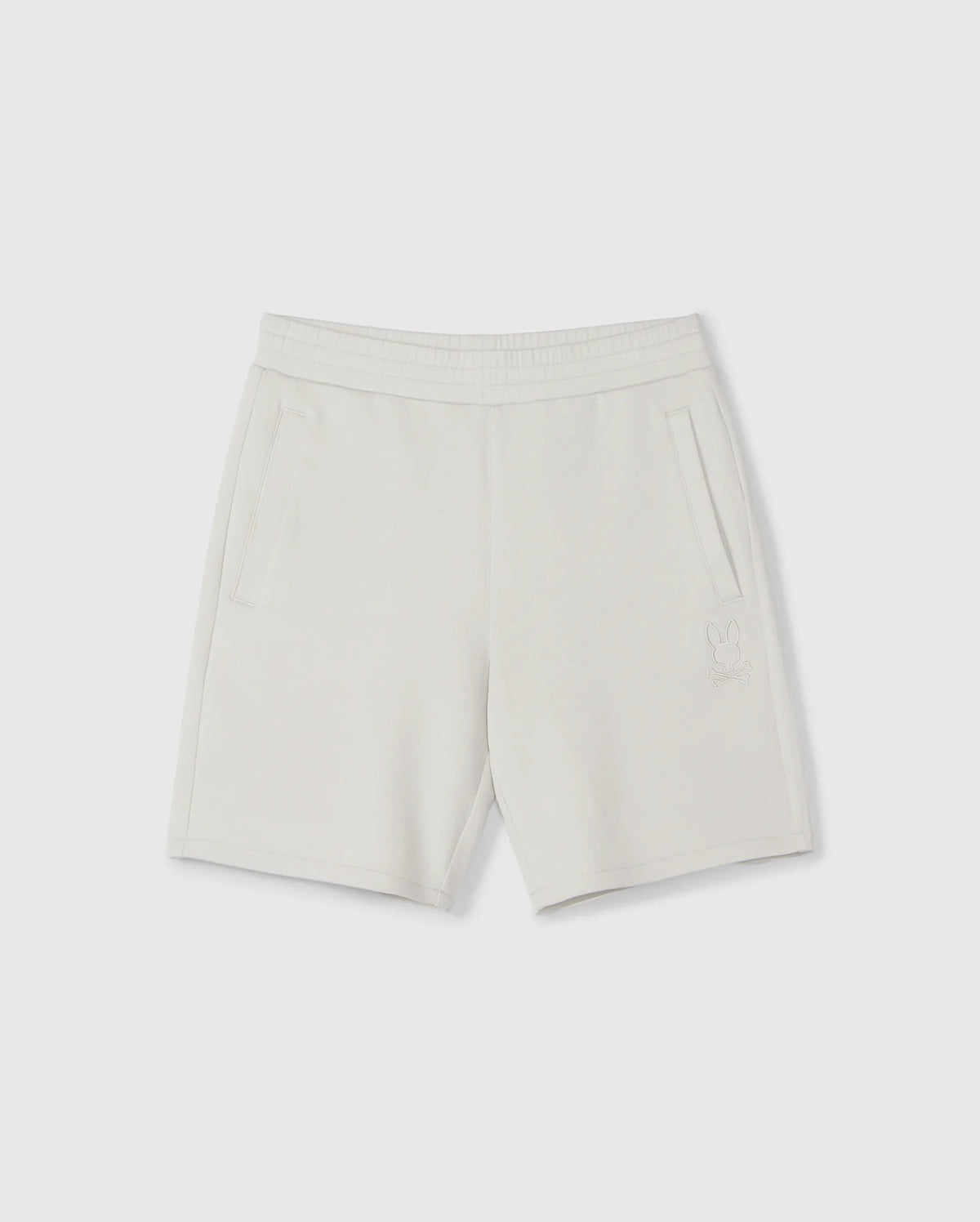 A pair of light gray, knee-length kids casual shorts with an elastic waistband and two side pockets. Made from a soft stretch modal-cotton-blend jersey, these Psycho Bunny KIDS LYONS SWEATSHORT - B0R578C200 feature a subtle embroidered design near the bottom of the left leg depicting a small bunny outline. Displayed against a plain white background.