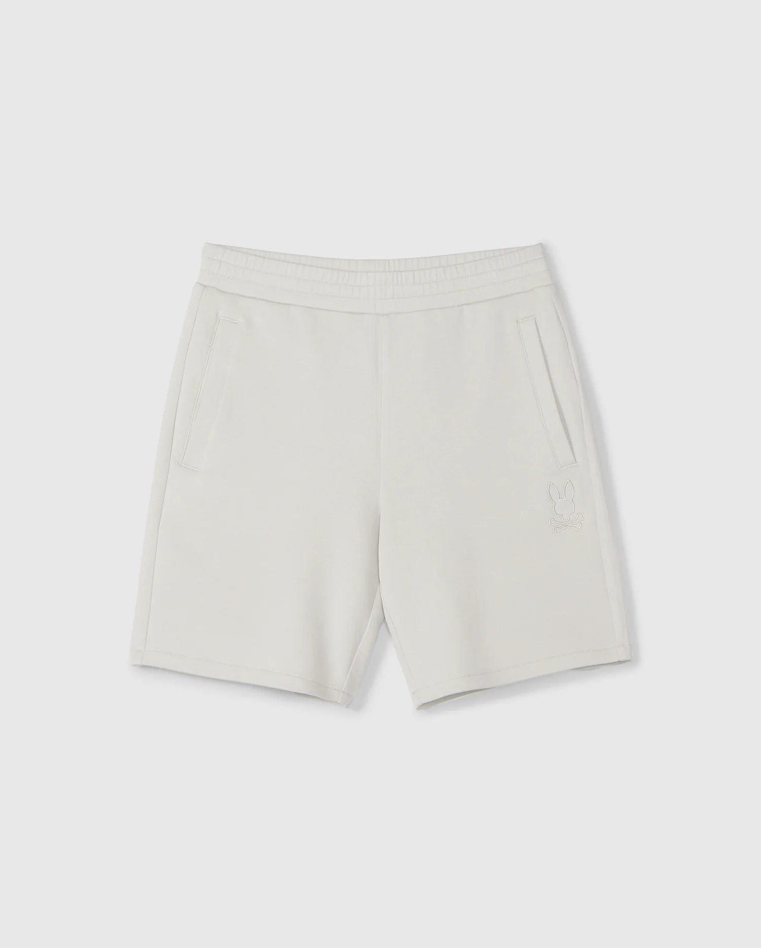 A pair of light gray, knee-length kids casual shorts with an elastic waistband and two side pockets. Made from a soft stretch modal-cotton-blend jersey, these Psycho Bunny KIDS LYONS SWEATSHORT - B0R578C200 feature a subtle embroidered design near the bottom of the left leg depicting a small bunny outline. Displayed against a plain white background.