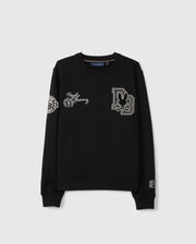 The KIDS ZACK VARSITY SWEATSHIRT by Psycho Bunny features chenille embroidery with a stylized letter “D” containing a rabbit, "Punk Bunny," and various decorative patches on the chest and sleeves. Its vintage-inspired logo is highlighted against the plain gray background of this black varsity sweatshirt.