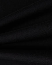 Close-up of Psycho Bunny's KIDS ZACK VARSITY SWEATSHIRT - B0S880D200 in black fabric, showcasing its visible texture with smooth folds that create parallel lines reminiscent of a varsity sweatshirt. The lighting accentuates the intricate weave, evoking the feel of chenille embroidery.