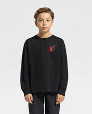 A young boy wearing the Psycho Bunny KIDS PIERCE LONG SLEEVE BACK GRAPHIC TEE - B0T178E200 with an embroidered bunny design is posed against a plain white background. He has short, light brown hair and gazes directly at the camera, proudly displaying the stylish red and black logo on his chest.