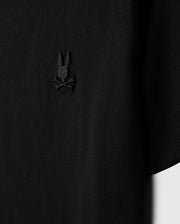 Close-up of a Psycho Bunny Kids Embroidered Classic Tee, product code B0U020AR00, crafted from luxurious Peruvian Pima cotton. It features a small bunny head with crossed bones design on the left chest and is displayed against a plain background for a timeless silhouette.