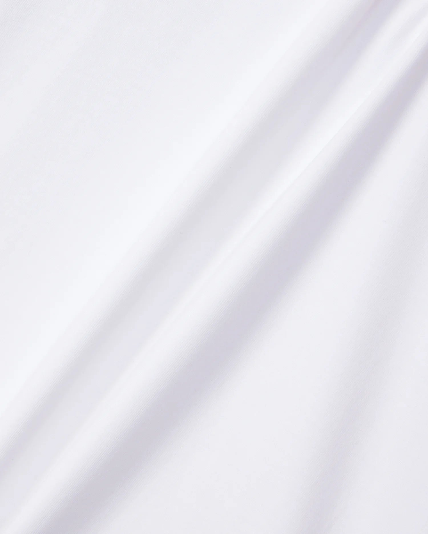 A close-up of the KIDS EMBROIDERED CLASSIC TEE - B0U020AR00 by Psycho Bunny, made from smooth Peruvian Pima cotton. The plain white fabric features subtle diagonal folds that are highlighted by gentle shadows in the lighting, showcasing its soft and clean surface. This texture is perfect for a classic tee or an embroidered chest Bunny design.