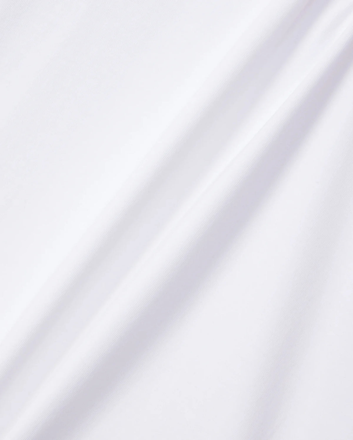 A close-up of the KIDS EMBROIDERED CLASSIC TEE - B0U020AR00 by Psycho Bunny, made from smooth Peruvian Pima cotton. The plain white fabric features subtle diagonal folds that are highlighted by gentle shadows in the lighting, showcasing its soft and clean surface. This texture is perfect for a classic tee or an embroidered chest Bunny design.