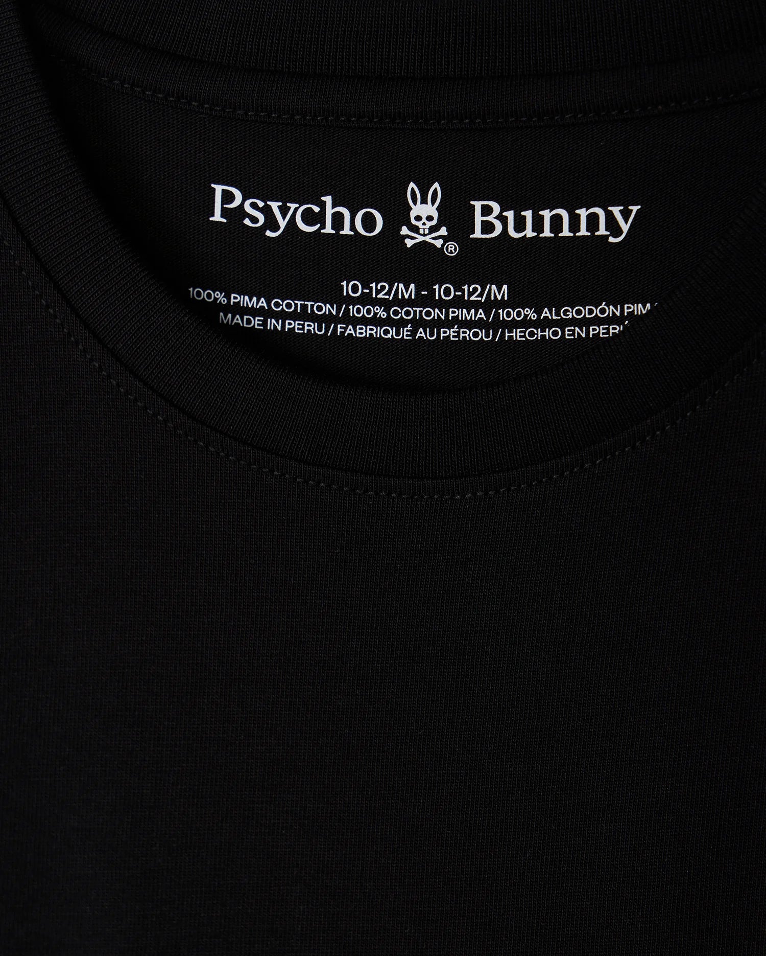 Close-up of a black KIDS HAWAII CITY TEE (B0U169Y1PC) by Psycho Bunny, crafted from Pima cotton with the brand name and bunny logo at the neckline. Includes size and fabric details, highlighting it's made in Peru, paralleling the volcanic islands' rich natural beauty.