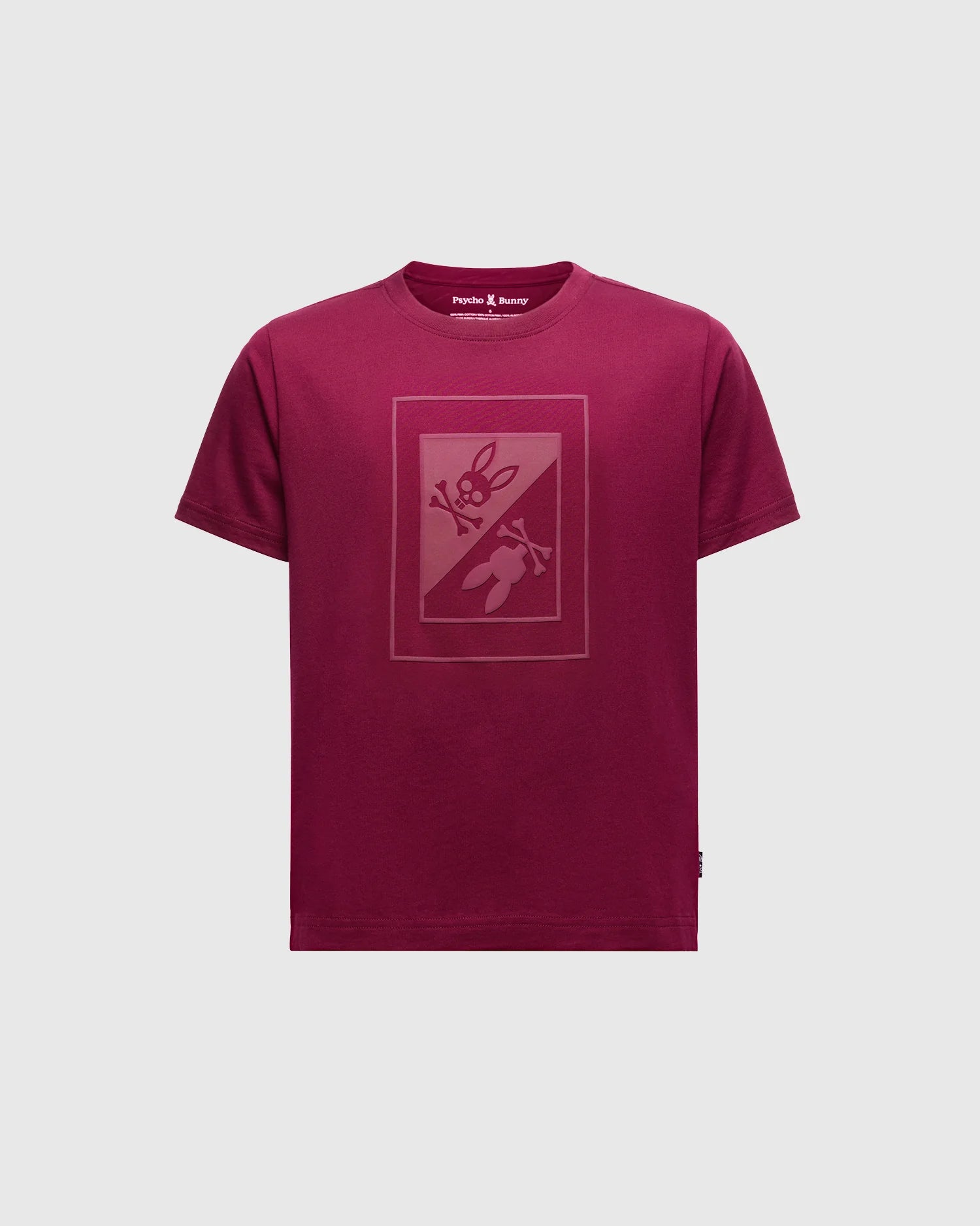 The Psycho Bunny Kids Dotser Printed Graphic Tee in maroon features a subtle bunny with a carrot on the front. Crafted from soft Peruvian Pima cotton, it includes a neck label reading "Purple & Reeny.