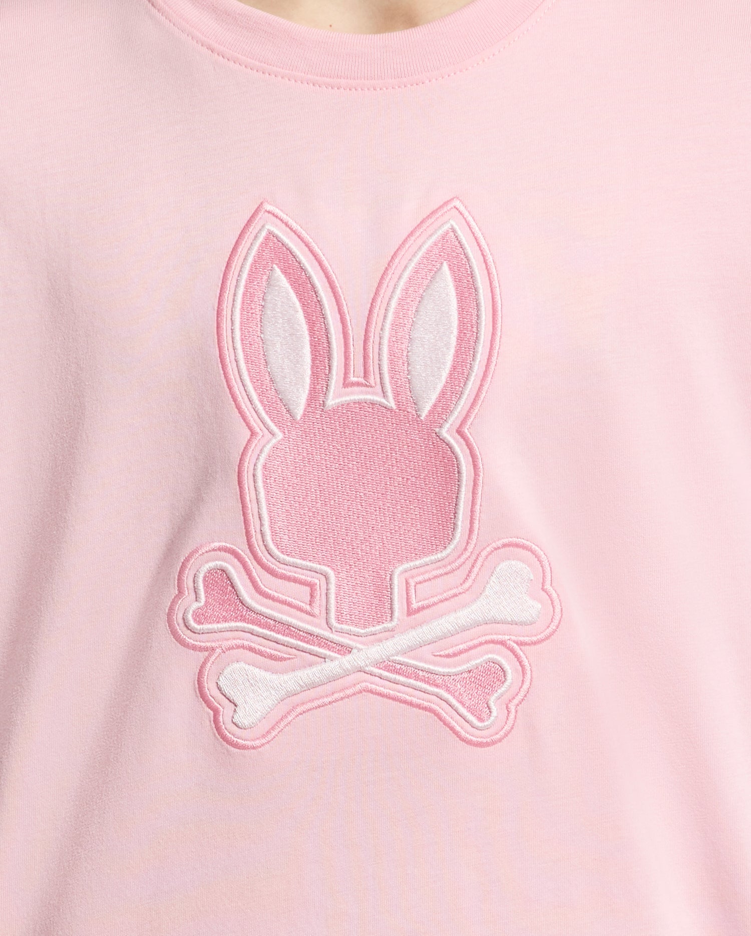 The KIDS NEW CASTLE EMBROIDERED GRAPHIC TEE by Psycho Bunny (B0U415F200) is a pink Pima cotton shirt featuring an embroidered stylized bunny head with crossbones in white and pink thread on the front.