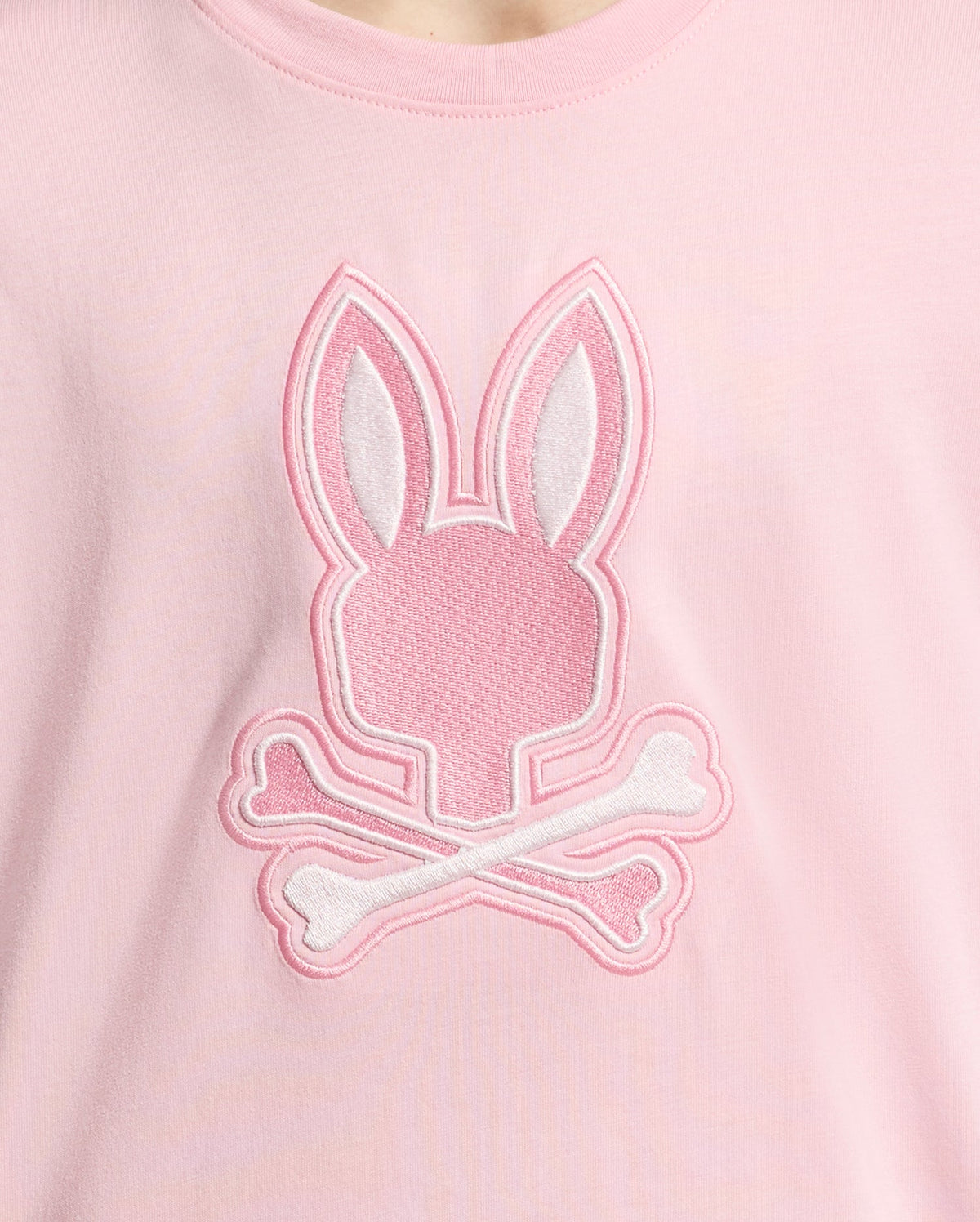 The KIDS NEW CASTLE EMBROIDERED GRAPHIC TEE by Psycho Bunny (B0U415F200) is a pink Pima cotton shirt featuring an embroidered stylized bunny head with crossbones in white and pink thread on the front.
