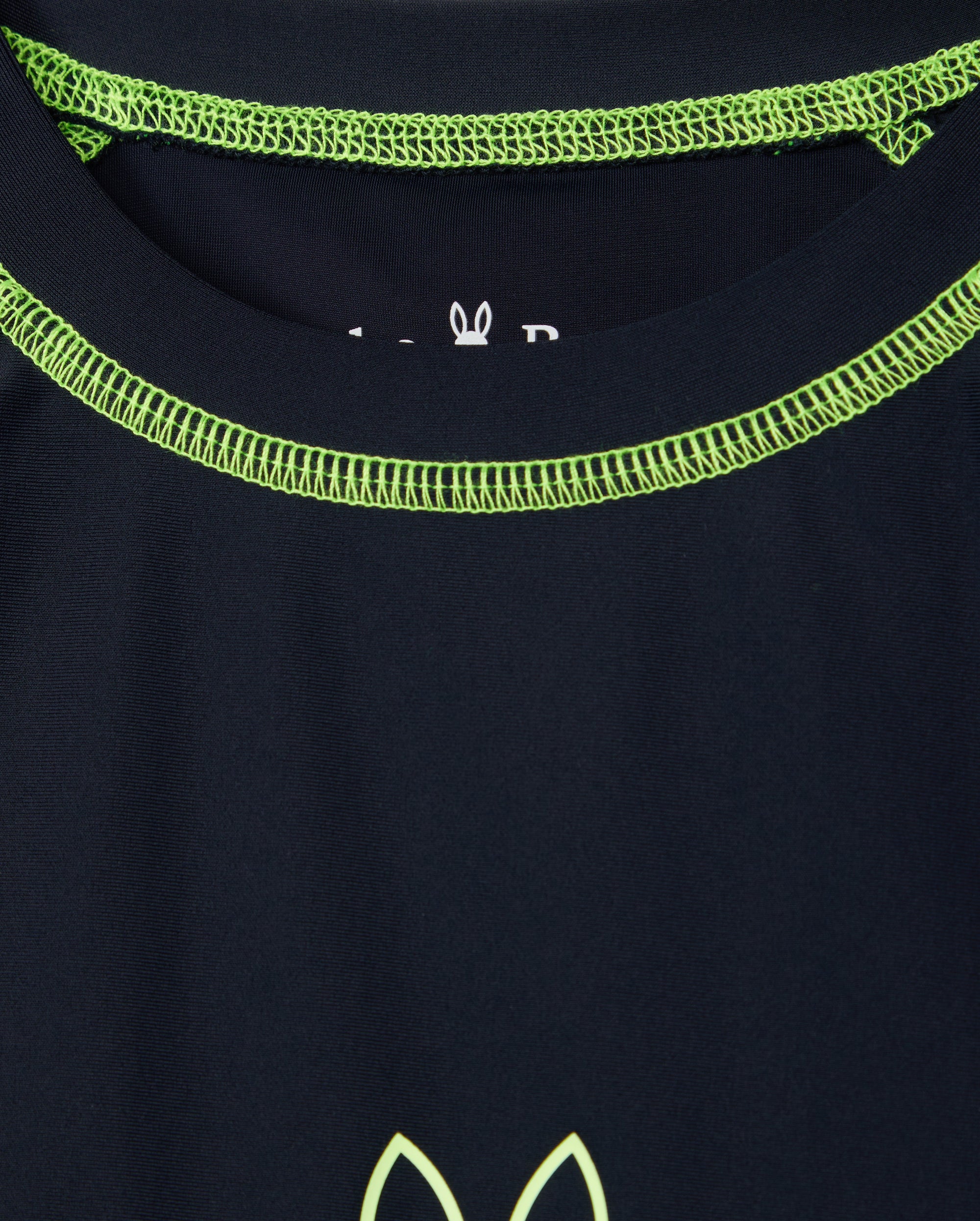 A close-up of the Psycho Bunny KIDS SHORT SLEEVE RASH GUARD in navy blue featuring lime green stitching around the neckline and a partial logo with a stylized animal design near the center.