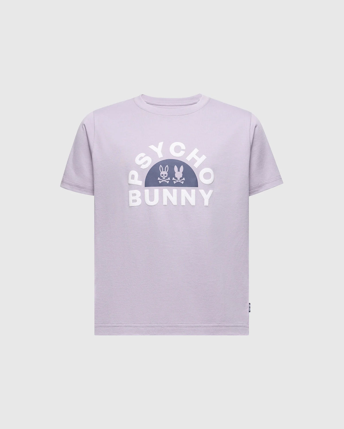 The KIDS GOLDIE GRAPHIC TEE by Psycho Bunny is made of soft Peruvian Pima cotton. The design showcases "PSYCHO BUNNY" in bold white letters, with two small bunny skull icons centered in a semicircle below, all on a lavender background.