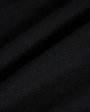 Close-up view of the fabric of the KIDS MALTON GRAPHIC TEE - B0U795D200 by Psycho Bunny, featuring a black hue with a smooth texture and visible fine weave, showcasing subtle diagonal folds and ripples, reminiscent of Peruvian craftsmanship.