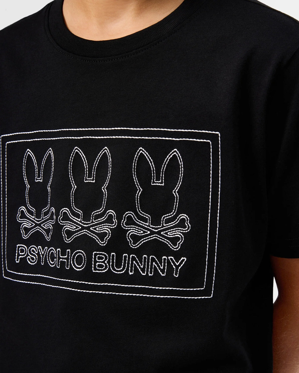 Close-up of the KIDS TACOMA GRAPHIC TEE - B0U909D200, made from soft Pima cotton, showcasing three outlined bunny skull logos above crossed bones with the "Psycho Bunny" text in crisp white stitching.