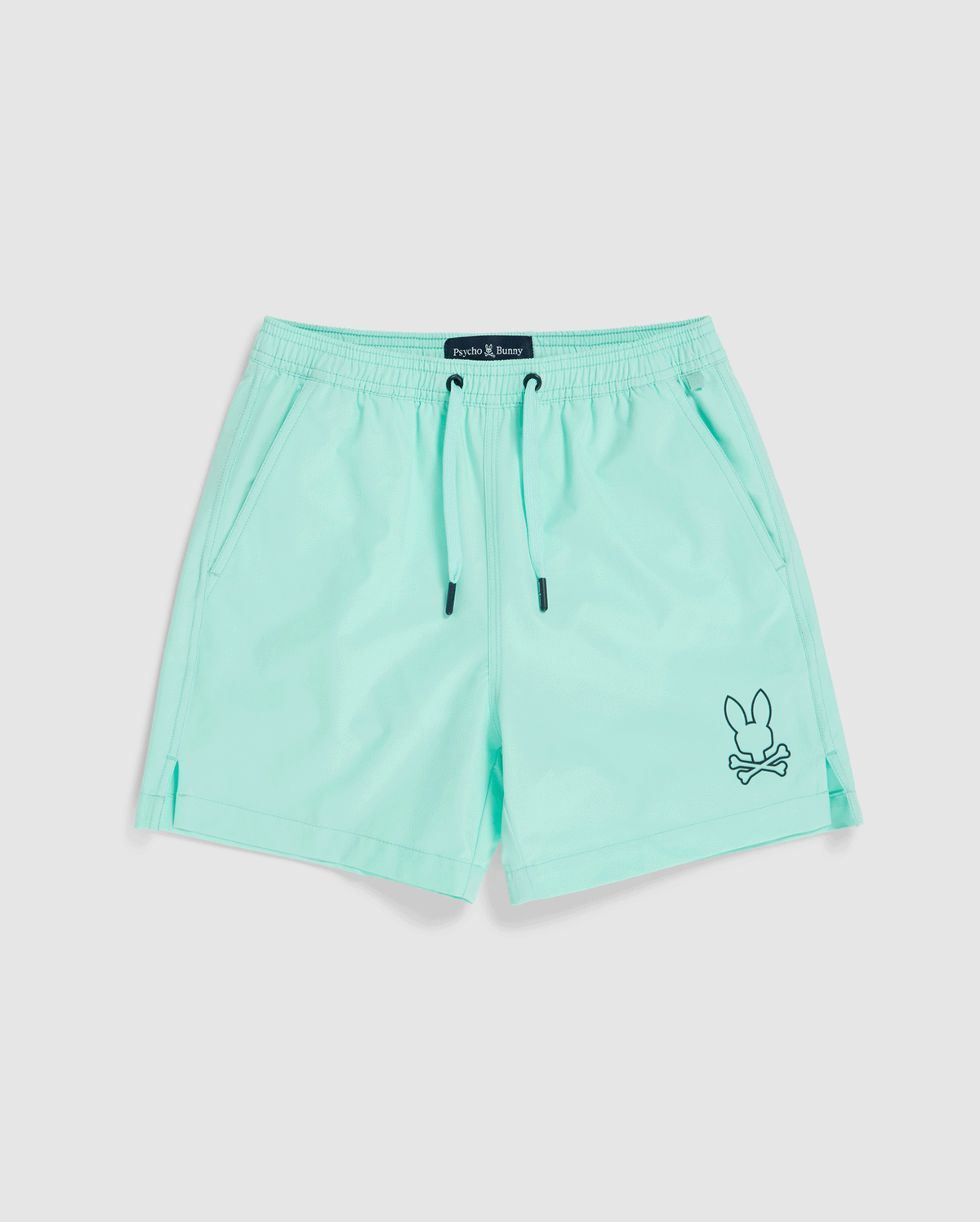 A pair of light turquoise, quick-dry KIDS PARKER HYDROCHROMIC SWIM TRUNK - B0W646C200 by Psycho Bunny with a black drawstring. The shorts feature two side pockets and a small embroidered bunny and crossbones logo in black near the bottom hem on one leg.