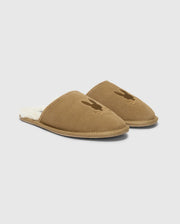 A pair of MENS SUEDE SLIPPERS by Psycho Bunny, crafted from cozy cow suede leather in brown with a soft, fuzzy interior. Each slipper is adorned with a subtle rabbit silhouette on the upper part, set against a clean white background.
