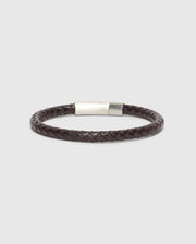 A stylish and elegant accessory, the MEN'S BRAIDED LEATHER BRACELET - B6A371E200 from Psycho Bunny showcases a sophisticated dark brown braided leather design with a sleek polished silver clasp, set against a minimalist light gray backdrop.