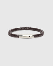 A classy statement piece, the MEN'S BRAIDED LEATHER BRACELET - B6A371E200 by Psycho Bunny features a dark brown braided leather design with a silver clasp, elegantly showcased against a plain white background.