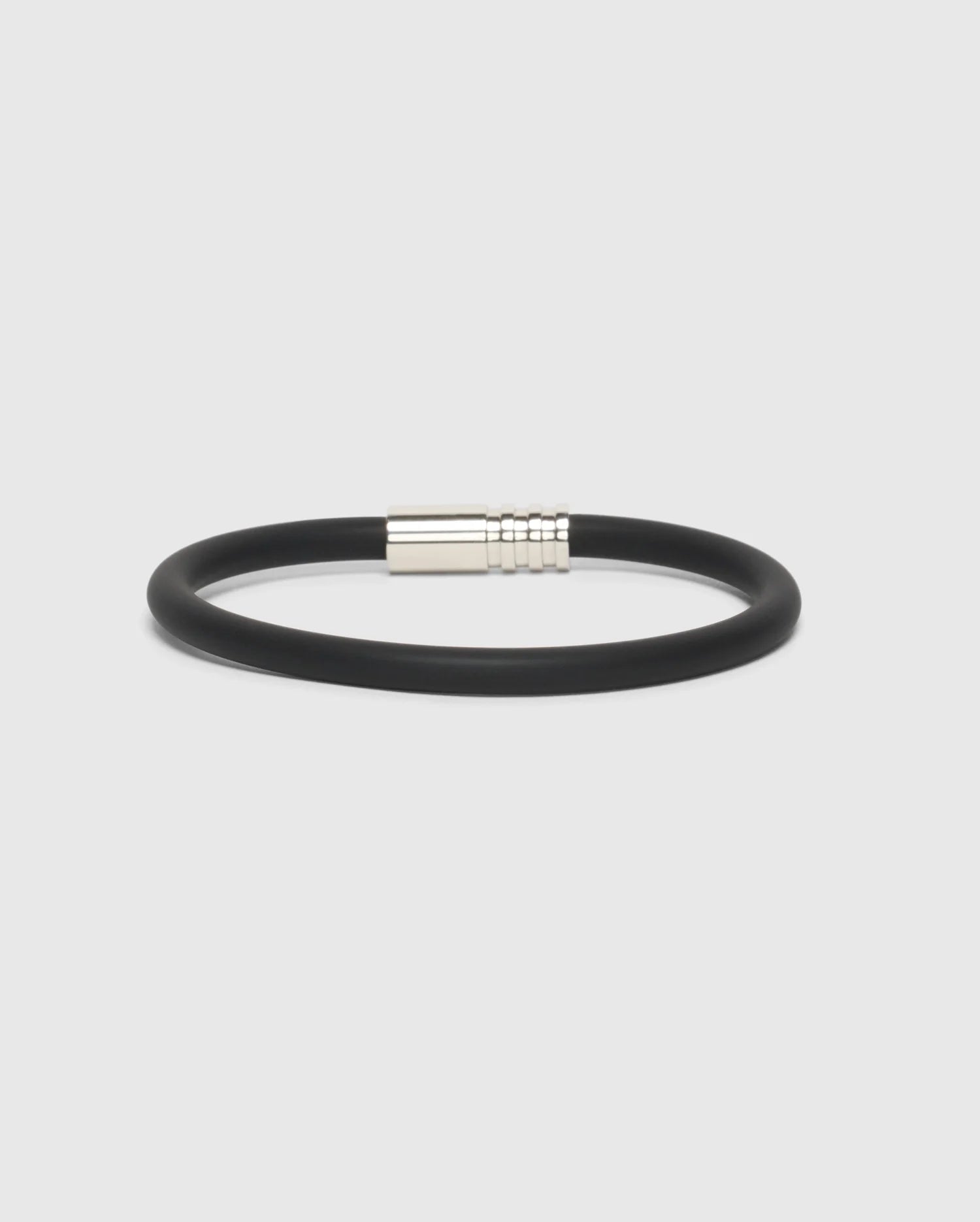 A sleek and modern silicone bracelet featuring a black band and a silver magnetic clasp, designed by Psycho Bunny, showcased against a plain white background.