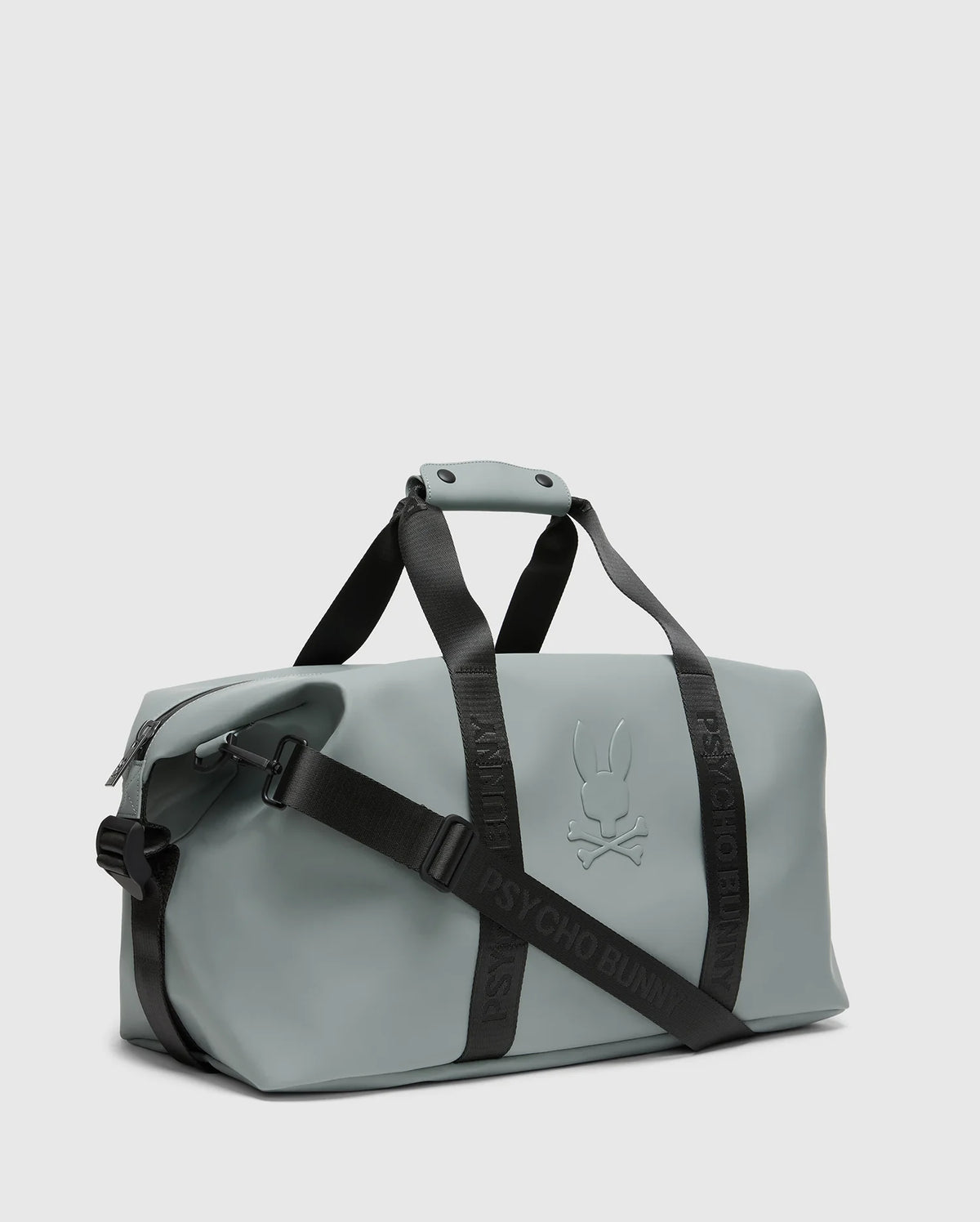 The Psycho Bunny Men's Duffle Bag (B6A472F200) is a gray carry-all with black adjustable straps and handles, featuring an embossed stylized bunny with crossbones. The straps display "PSYCHO BUNNY" boldly, complementing its minimalist design. Ideal for efficient packing on the move.
