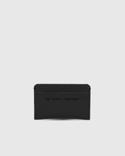 The Psycho Bunny MENS RUBBERIZED CARD CASE - B6A473F200, shown in black against a white background, offers peace of mind with its sleek design. Embossed with "THE BOLD STANDARD," this minimalist card case keeps your essentials safe.