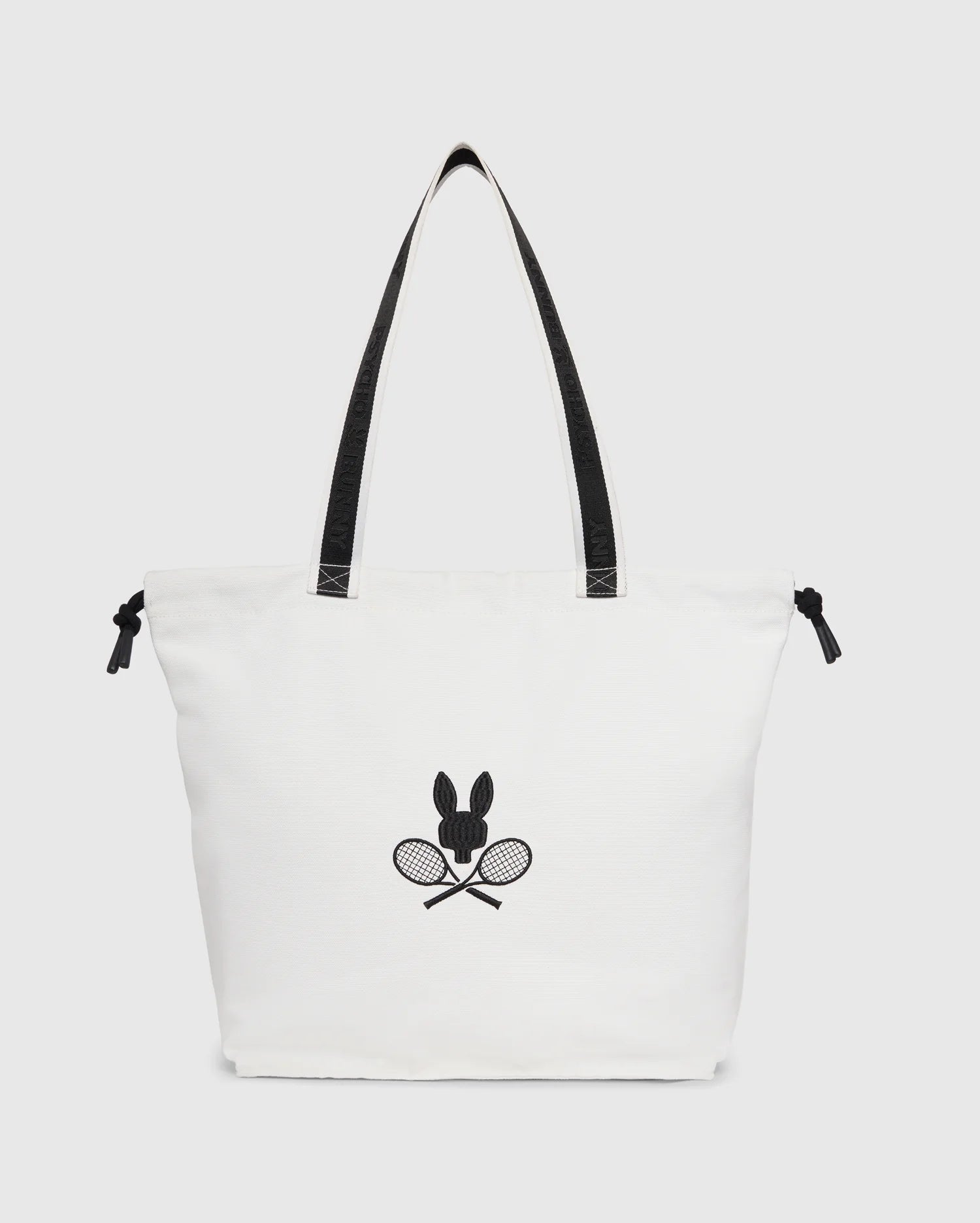 The Psycho Bunny TENNIS TOTE - B6A596C200 is a stylish canvas tote with black handles, featuring an embroidered minimalist logo of a rabbit above crossed tennis rackets.