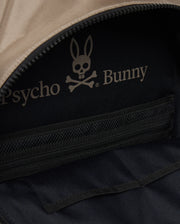 Close-up of the inside of an urban backpack featuring a black fabric lining with a zippered pocket. The lining has a logo with a bunny's head above crossbones and the text "Psycho Bunny." The zipper of the pocket is partially visible, complemented by a padded laptop compartment for added style. This is the MENS DOME BACKPACK - B6A628Z1BP by Psycho Bunny.